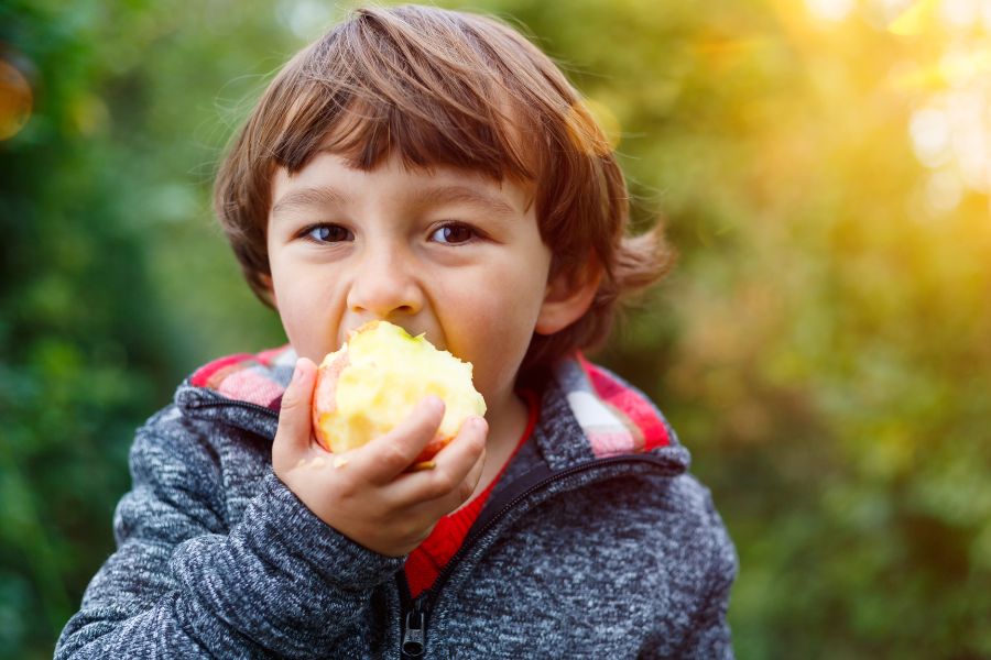niño mordiendo una manzana