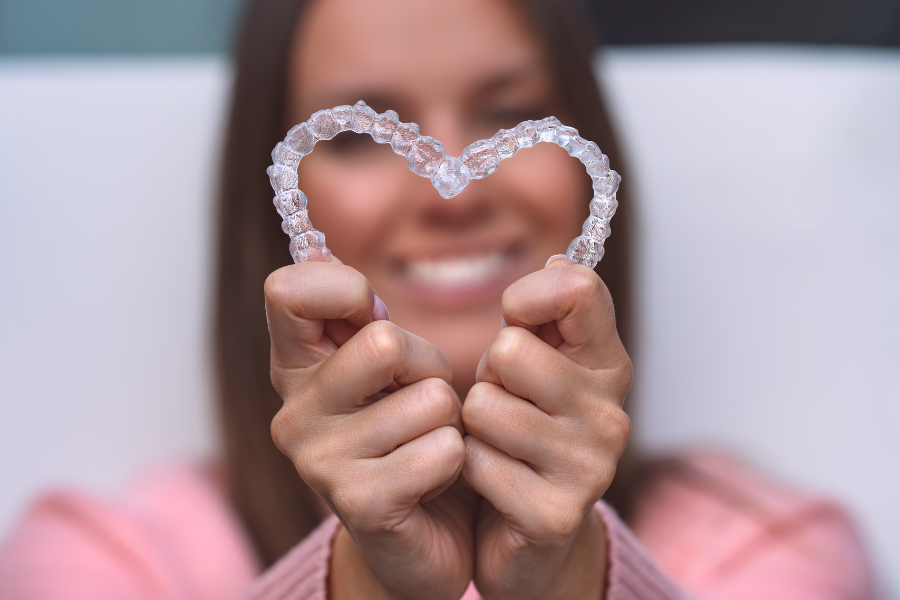 mujer muestra la ortodoncia invisible en Invisalign y lo coloca en forma de corazón