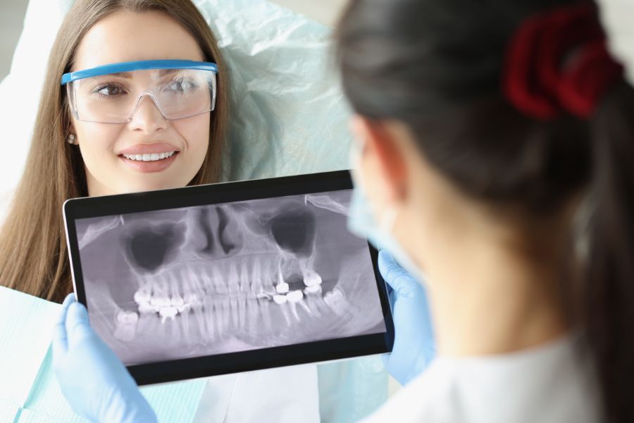 dentista mira radiografía de la boca y dientes de una paciente